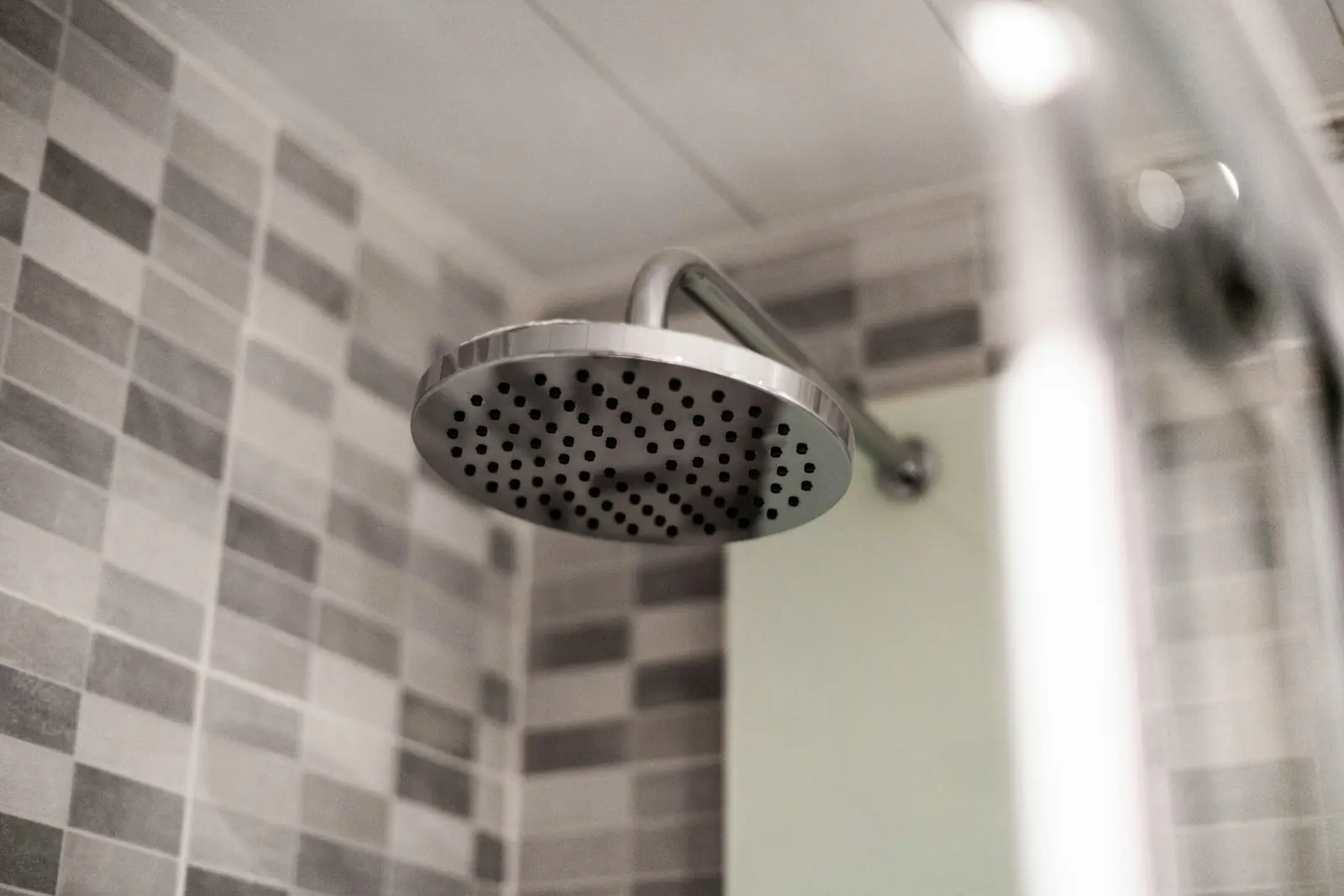 Chrome overhead shower head against grey wall tiles