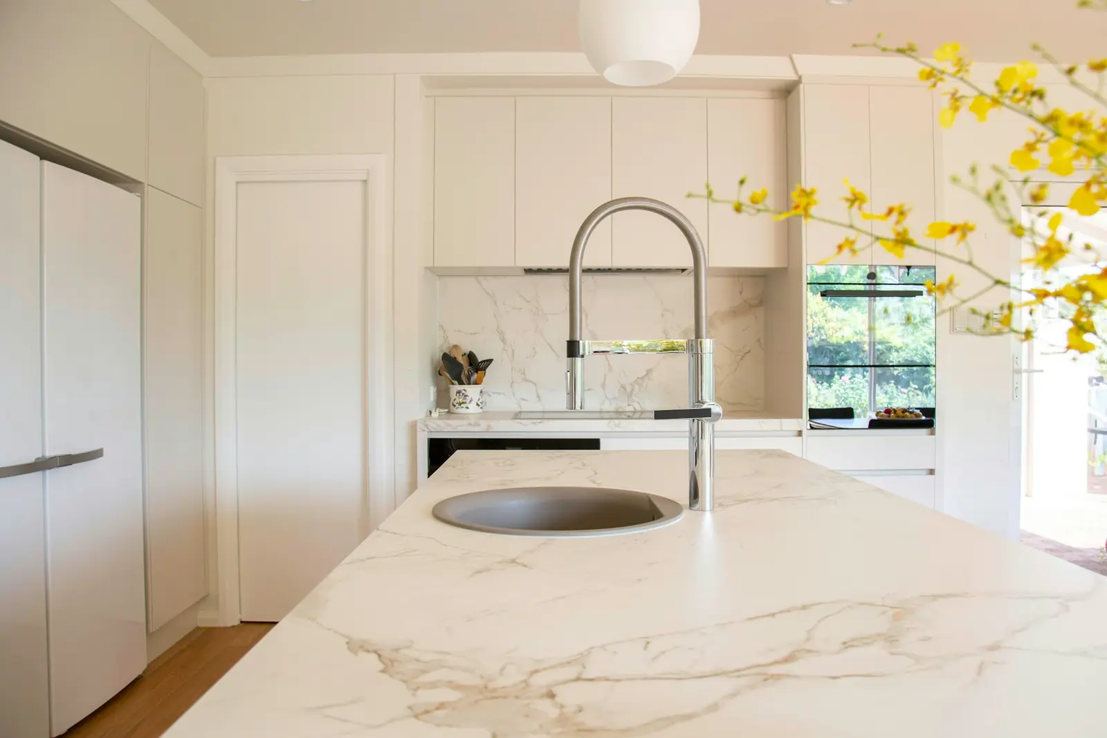 Round sink and pull-out tap set into a marble-effect kitchen island